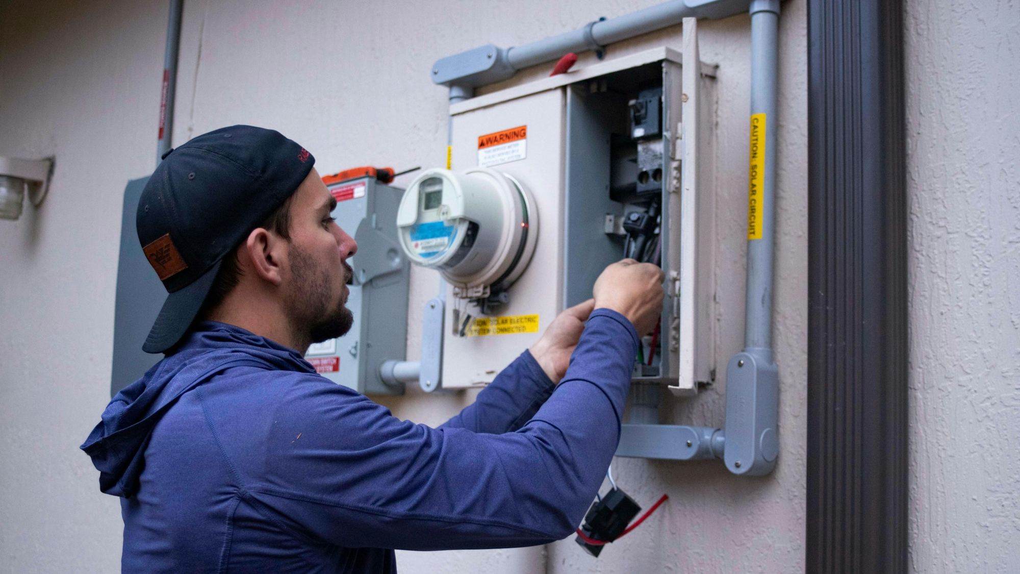 An electrician working on an electricity meter and wiring